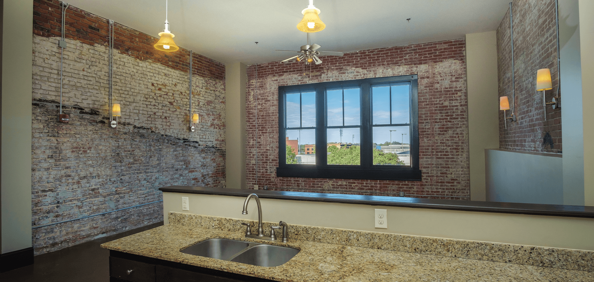 Living room view of 22 Monroe apartments with industrial brick walls and sconce lighting