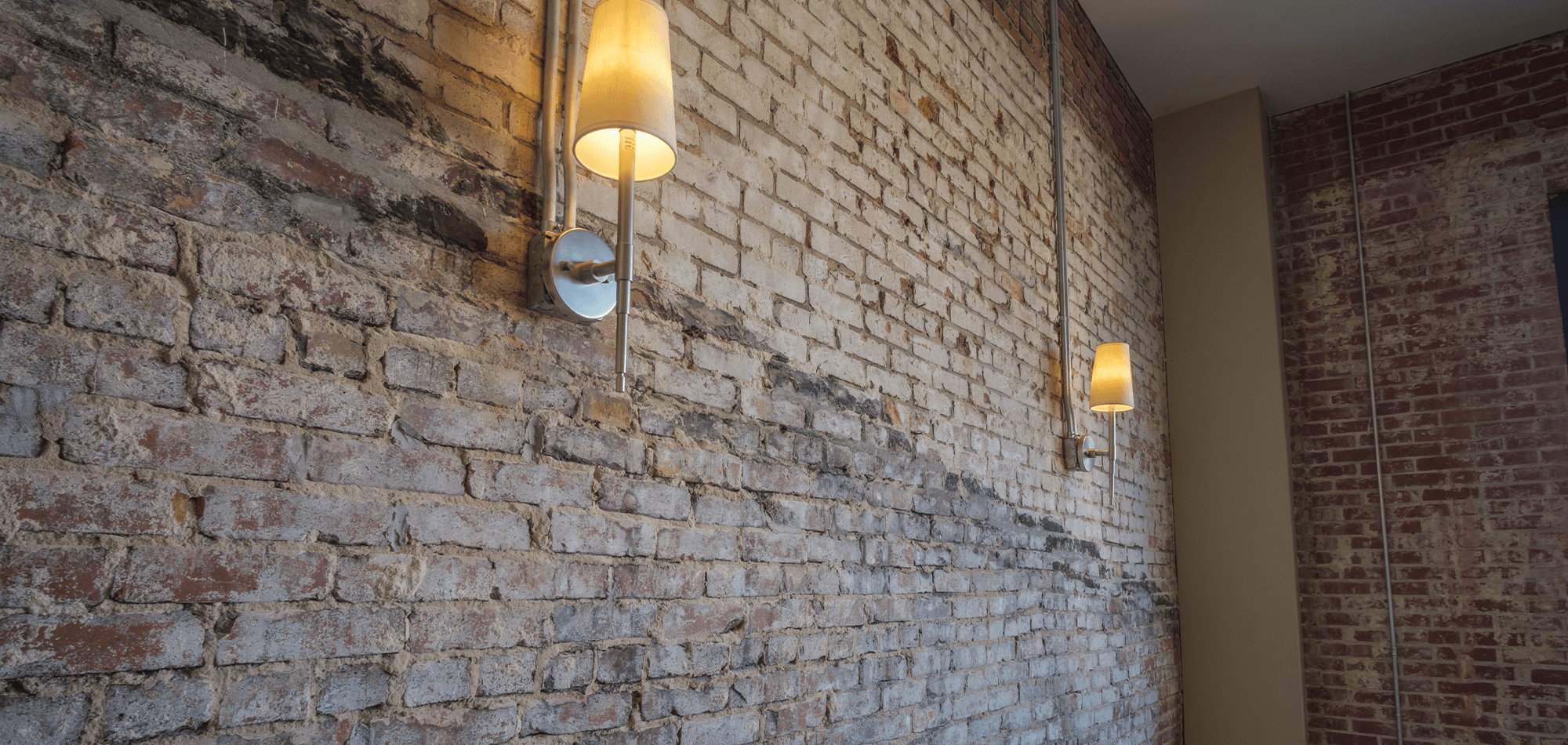 close up of brick industrial wall and wired sconces in the 22 Monroe living room