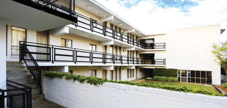 Exterior view of the courtyard of Perry Street Flats in Montgomery Al showing the white brick exterior and green space.