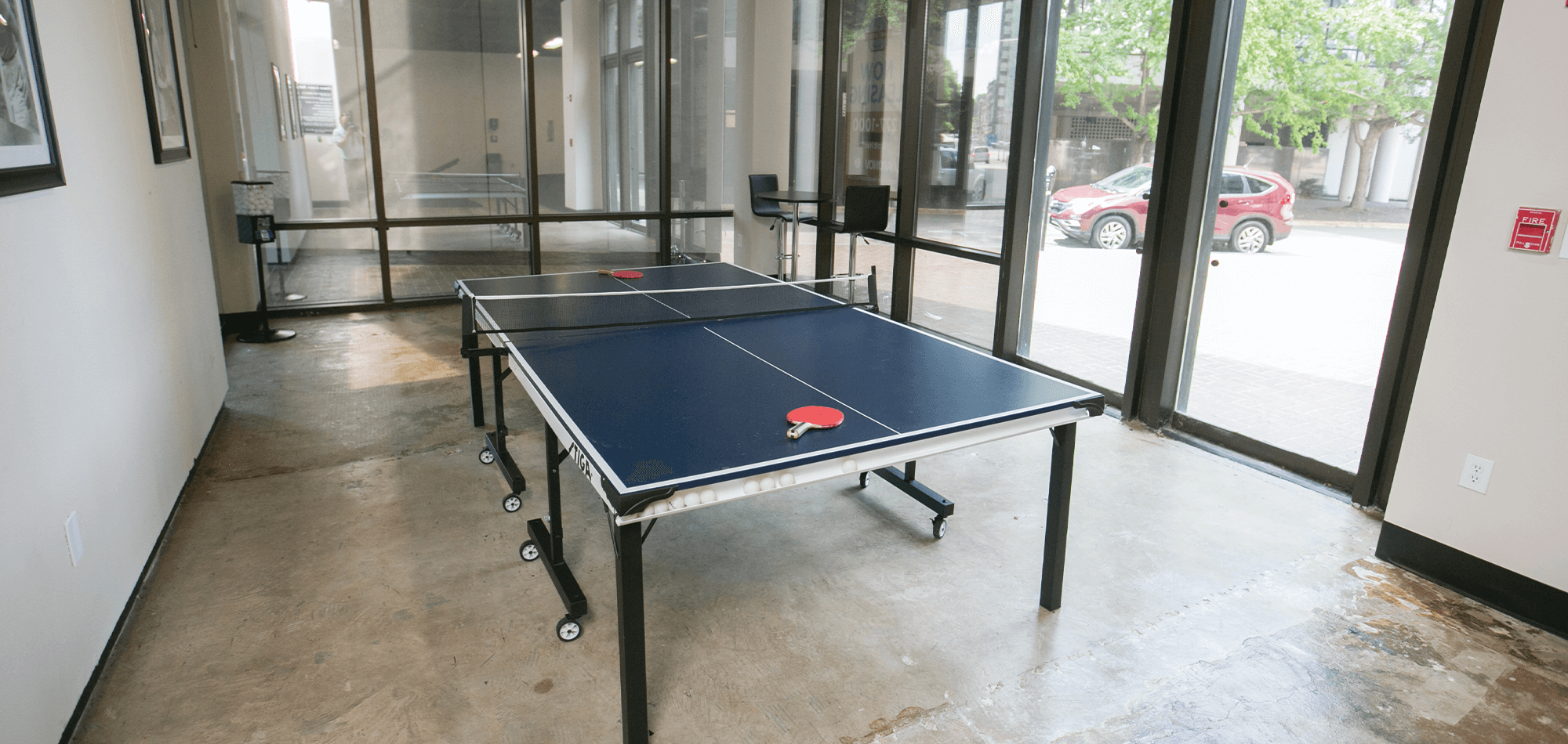 a ping pong table in the 40 Four building with sealed concrete floors and large glass windows