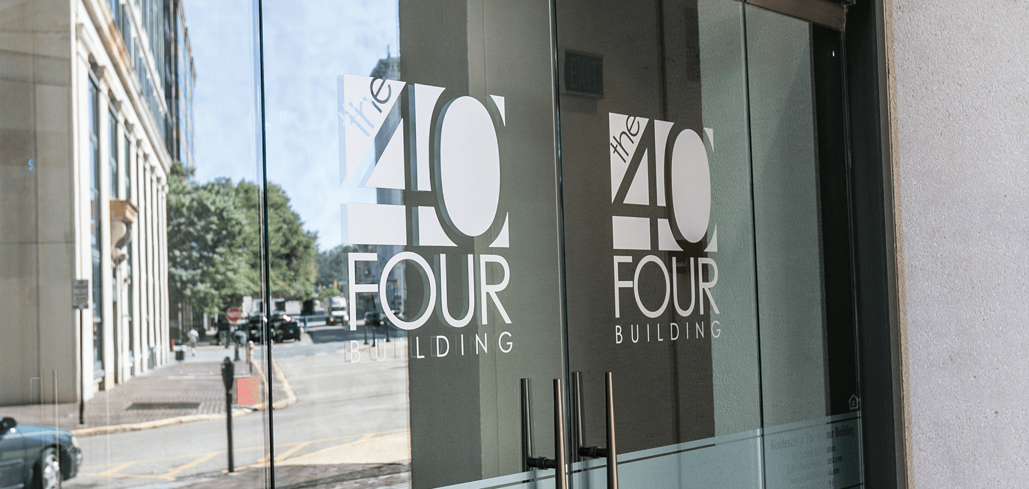 Entrance to the 40 Four building with glass doors and the logo in white on the front